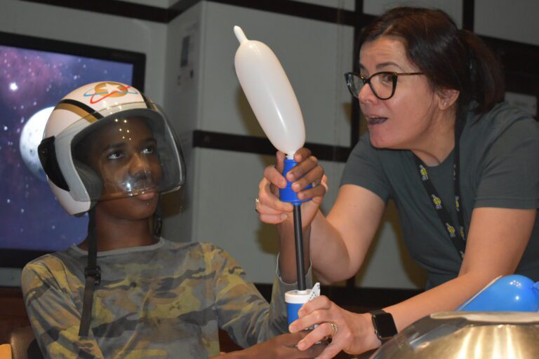 boy inflating balloon with space themed helmet on