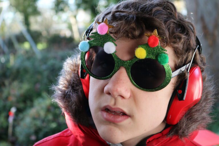 child wearing headphones with Christmas tree glasses