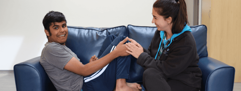 boy and woman holding hands on a sofa happily