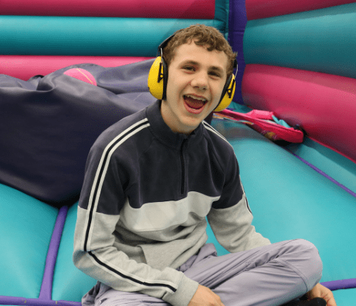 happy child sitting on floor of bouncy castle wearing headphones