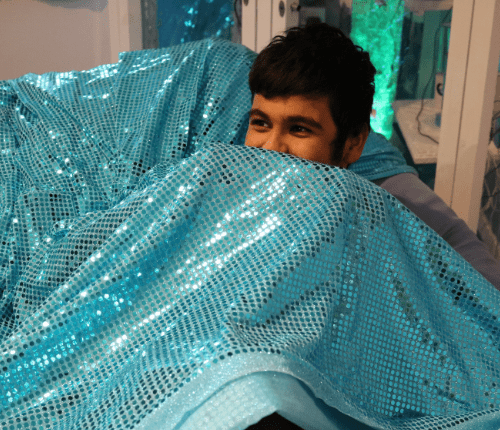 boy under shiny blue blanket