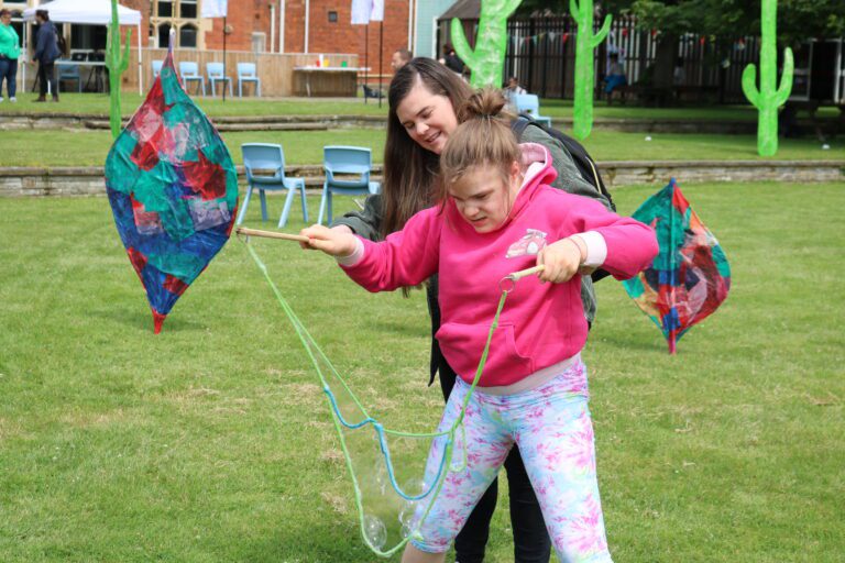a women helps a child use rope to create bubbles