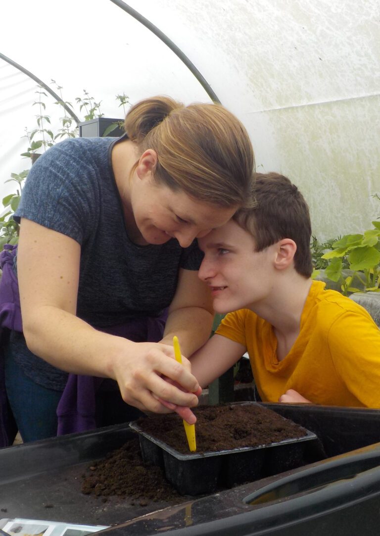 a disabled child and a woman working with dirt in a green house
