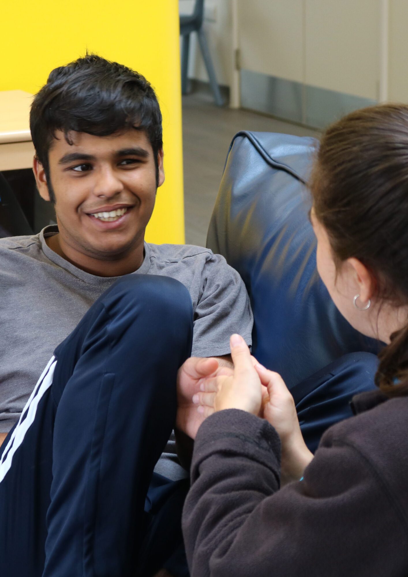 young boy sitting on sofa, shaking hands and and speaking toa women
