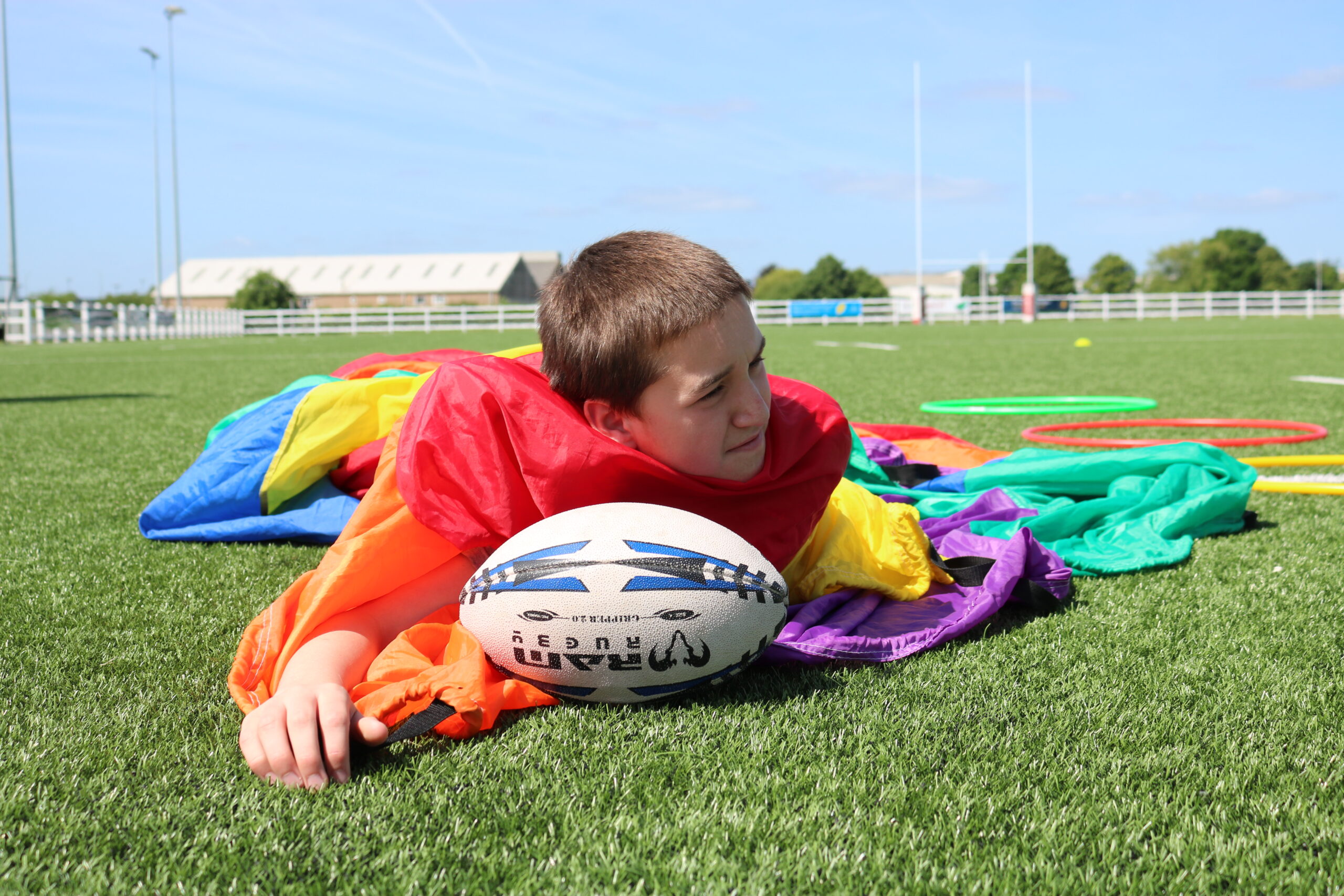 boy laying on field with rugby ball